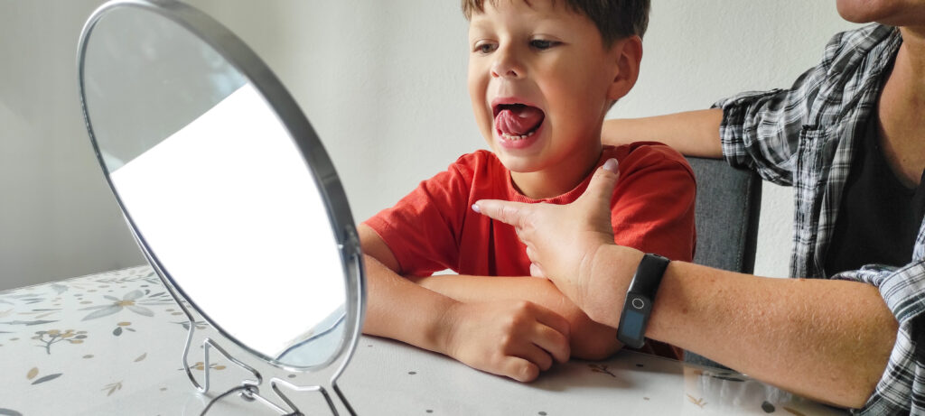Child practicing speech sounds while looking in a mirror