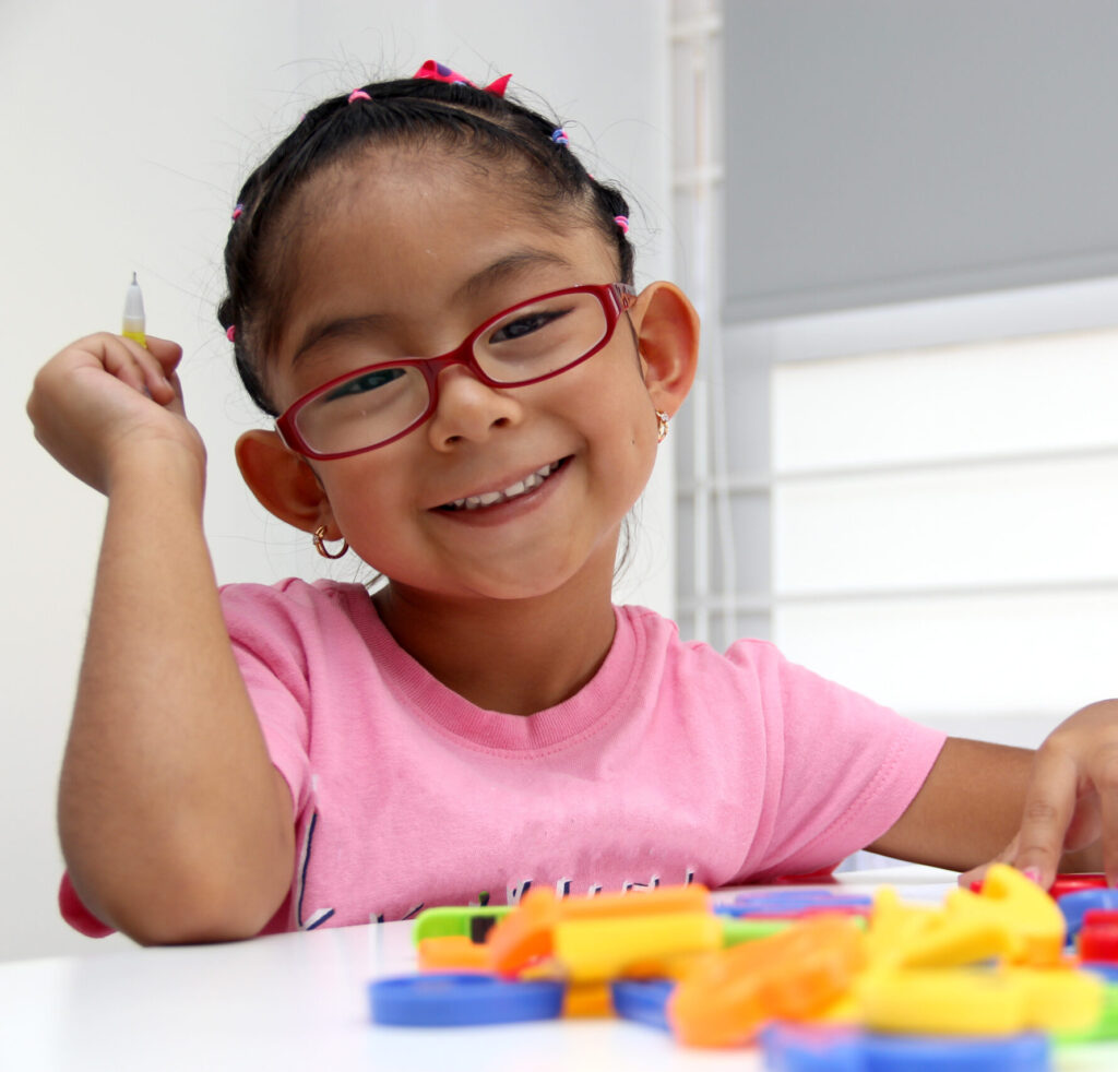 Young child drawing at a desk during a learning activity